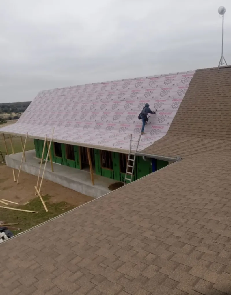 Worker preparing underlayment for a metal roof installation in Poplar Grove